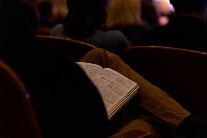A student holding a bible in their lap during chapel