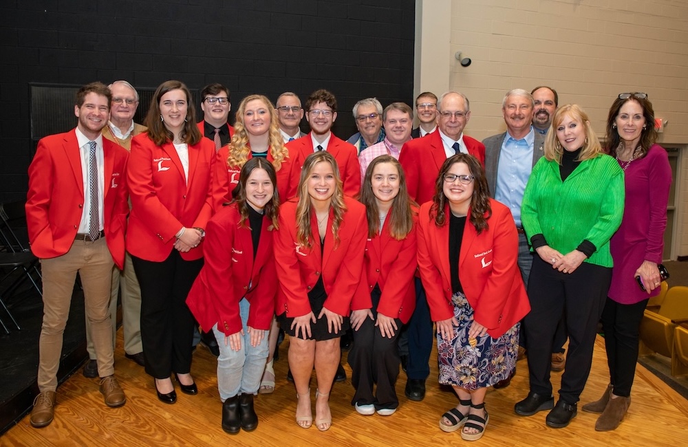 A group of people pose for a photo in their lads to leaders jackets