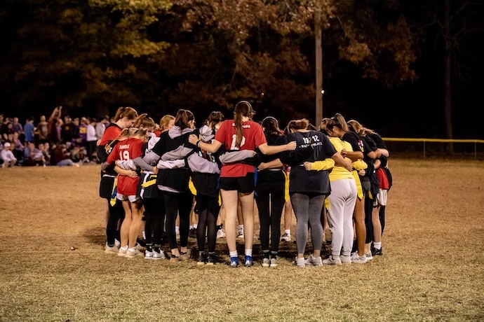 A group of students pray before a flag football game