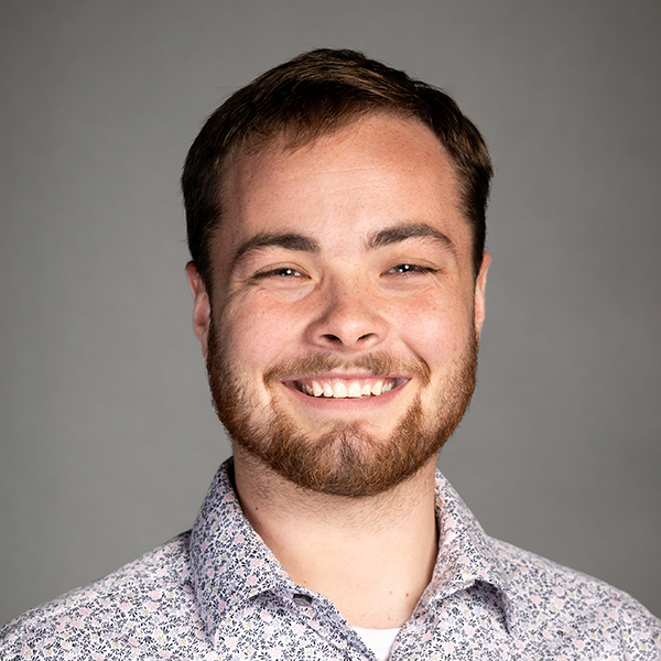 Garyson Campbell, a smiling young man with a light bear and mustache and short hair