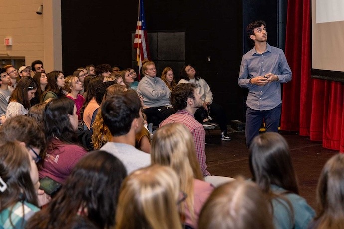 A group of students watch a presentation on the stage in Loyd Auditorium