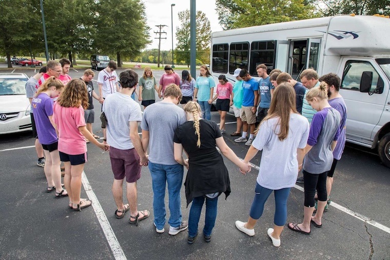 A group of students pray before embarking on a missions trip