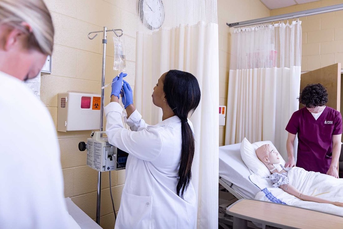 A nursing student hangs an iv bag for a patient