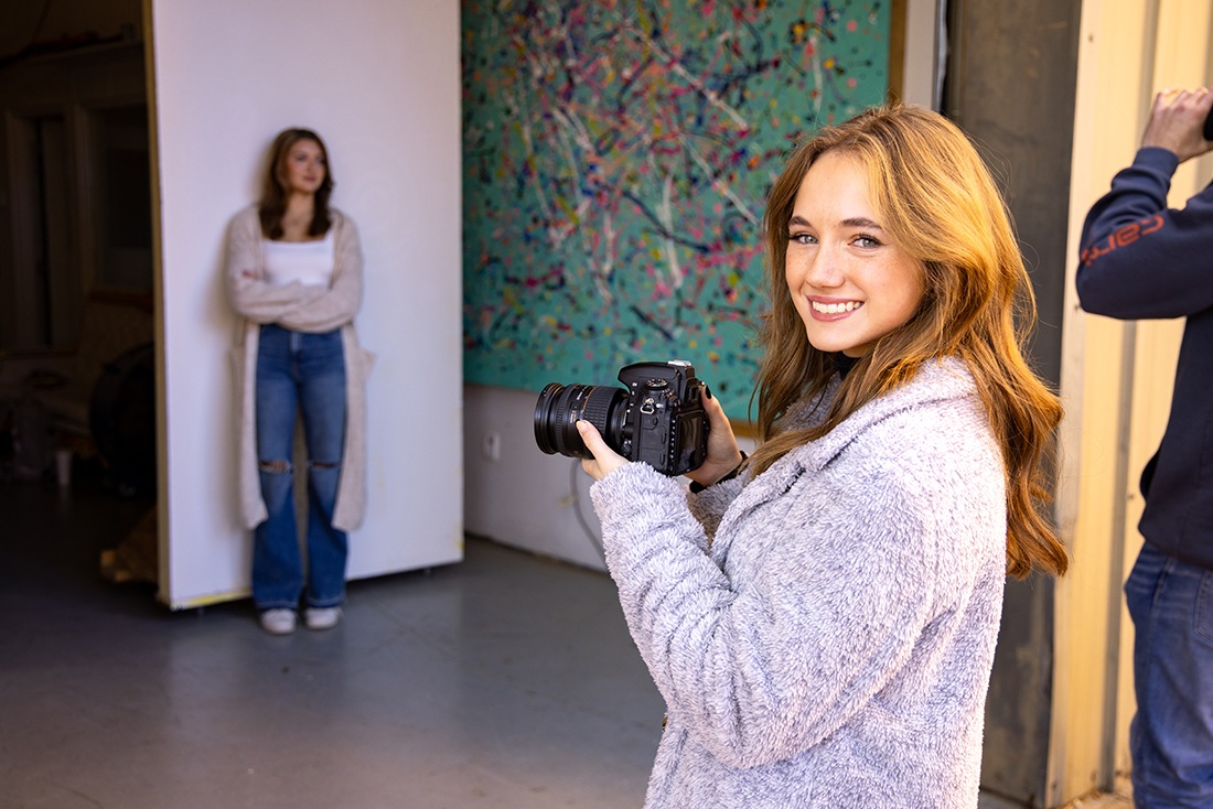 A photography student poses for a photo during a photo shoot