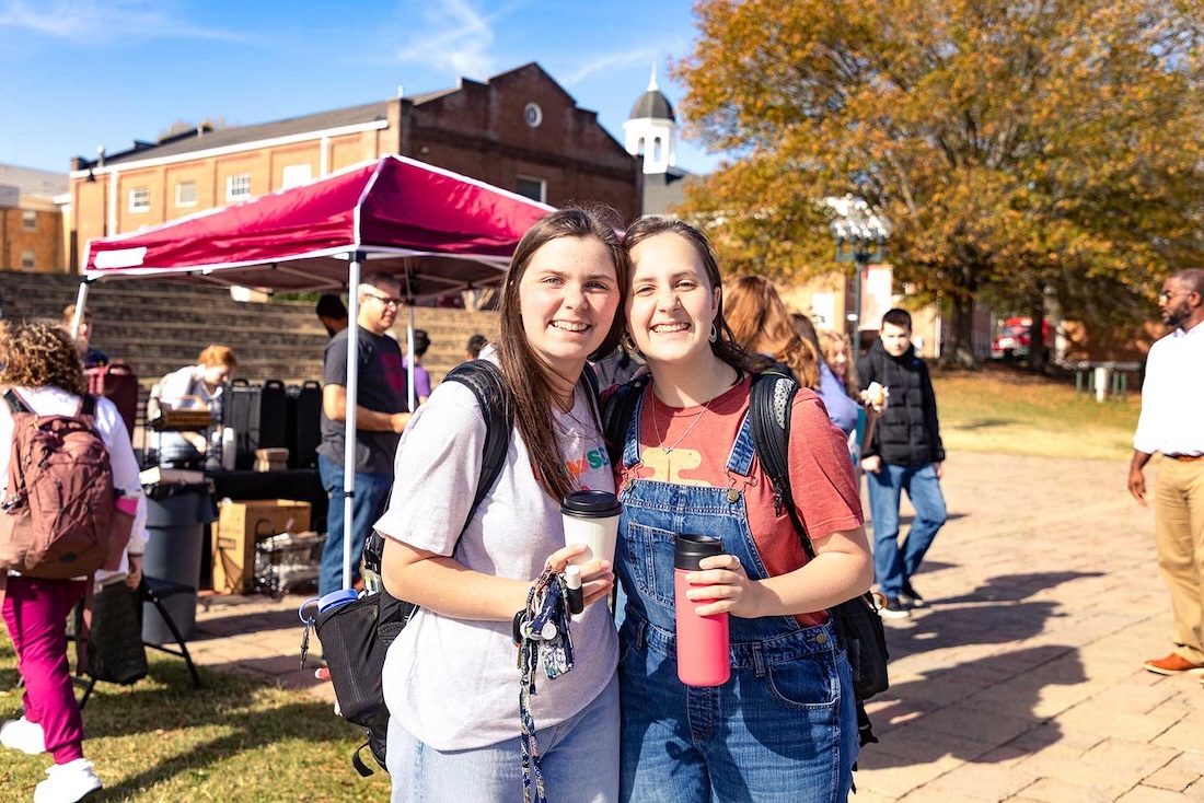 A couple of students pose for a picture while enjoying some coffee in the commons during an event