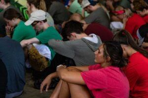 students sitting on the ground praying