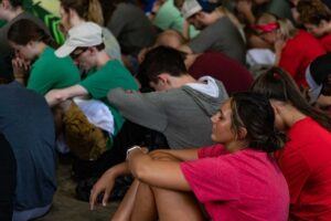 students sitting on the ground praying