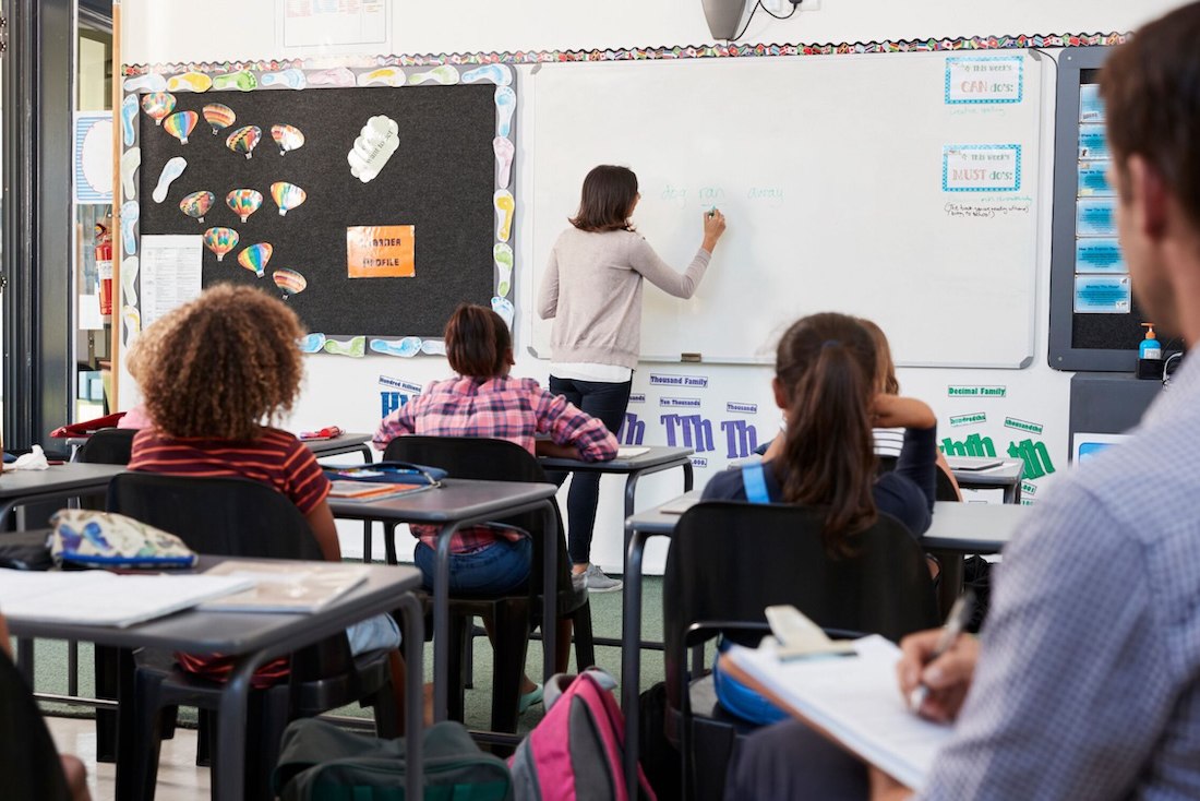 A teacher writing on the white board in front of the class