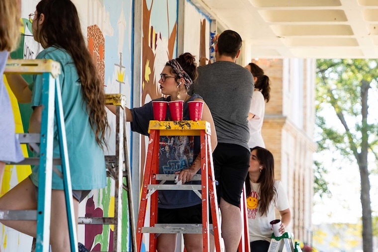 A group of students paint the windows of Wallace-Gano Dining Hall as part of the yearly 